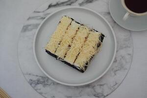 A piece of black cake topped with shredded cheese photo