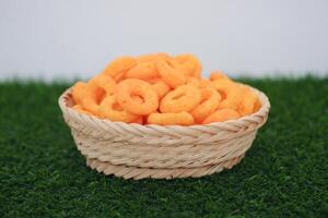 snack cheese crackers in a basket on green grass with white background. photo