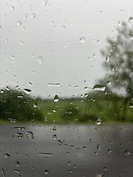 Raindrops on a windowpane overlooking blurred trees photo
