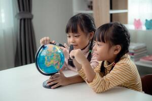 Two Asian little girl is learning the globe model, concept of save the world and learn through play activity for kid education at home. photo