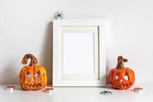 Halloween composition with ceramic pumpkins jack lantern and frame on table wall background. Greeting card template photo