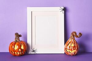 Halloween composition with ceramic pumpkins jack lantern and frame on table wall background. Greeting card template photo