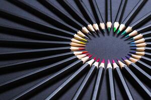 Colored pencil set arranged in circle on black background. Stationery minimal round frame photo