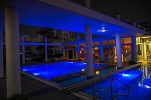 view of the night illuminated pool near with a residential complex resort photo
