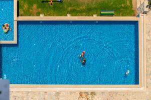 A top down shot directly above an empty pool, surrounded by green grass and trees photo
