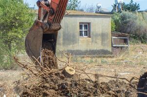 Gazeveren Cyprus 03.07.2024 - excavator uproots the roots of orange trees photo