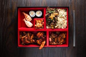 Bento Set include fried rice, Beef Bulgogi, grilled seafood and maki roll with chopsticks served in dish isolated on wooden table top view of korean food photo