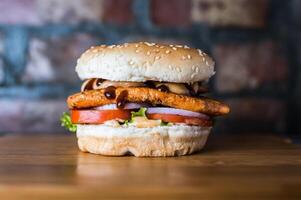 Grilled Chicken Burger include chicken patty, mayonnaise, lettuce leaf, tomato and onion isolated on wooden board side view of unhealthy junk fastfood photo