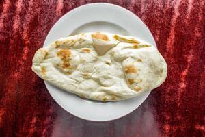 Plain Naan or sada khamiri roti served in plate isolated on table background top view of bangladeshi, indian and pakistani food photo
