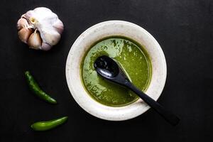 Green Chilli Paste or sauce with garlic and spoon served in dish isolated on dark background top view of chinese food photo