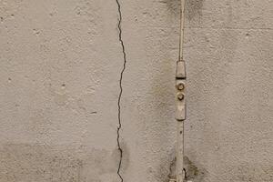 crack in a wall with a bolt sticking out of it photo