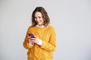 Smiling Woman Using Smartphone. A joyful young woman with curly hair using a smartphone. Ideal for depicting modern communication, technology, or social media themes. Isolated on a white background. photo
