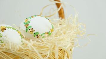 Handmade art. Thread embroidery on eggs. Easter in a wicker straw basket there are white eggs with a beautiful decoration of ribbons to embroider at home video