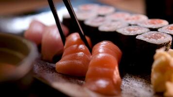 Sushi rolls are rotated in package after delivery. Philadelphia roll in sushi set close up. Traditional Japanese food. Japanese kitchen with sea food. Taking one sushi roll from set using chopsticks. video