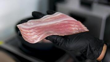 Raw bacon. Raw bacon strips sizzling in cast iron pan. Close up video