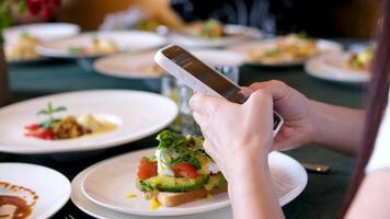 Female hands with a phone during breakfast at the buffet dinner table choose a dish write a message use the Internet video