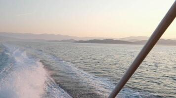 The ferry gracefully plows through the waves, leaving behind a mesmerizing trail of splashing water, with blurred white railings in the foreground video