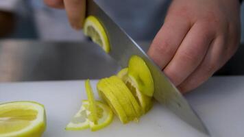 Cut lemon into slices. Lemon is cut on a plastic cutting board with sharp kitchen knife video