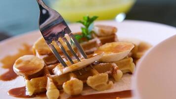 woman's hand is cutting the ice cream on a banana bread waffle , preparing to eat. Pricking a delicious breakfast on a fork video