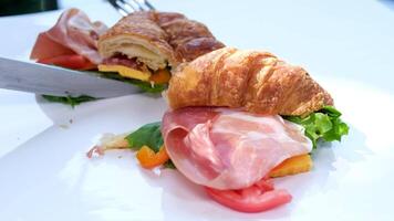 Zoom-in close up view of breakfast meal. croissant sandwich with bacon and scrambled eggs. Original tasty meal with meat served at Bali cafeteria in morning time video
