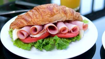Zoom-in close up view of breakfast meal. croissant sandwich with bacon and scrambled eggs. Original tasty meal with meat served at Bali cafeteria in morning time video