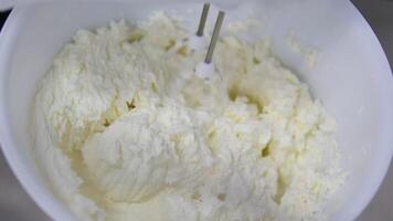 White butter cream in a metal bowl. Beating cream cake. Mixer whisk in cream. video