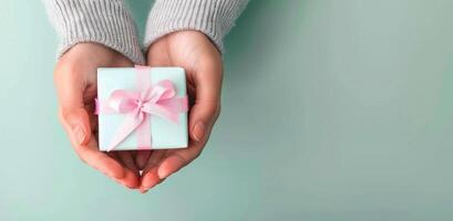 Delicate Gift Wrapped in Pink Ribbon Held by Young Person in Cozy Indoor Setting photo