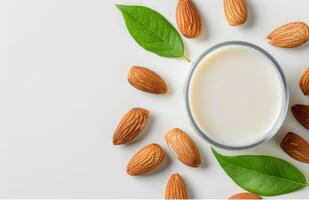 Creamy Almond Milk Surrounded by Almonds and Fresh Leaves on a White Background photo