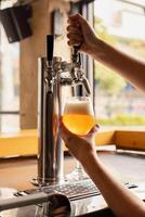 Delicate hands of woman pouring fresh beer from tap into glass in a pub. photo