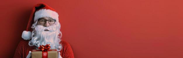 Santa Claus Holding a Gift Against a Red Background photo