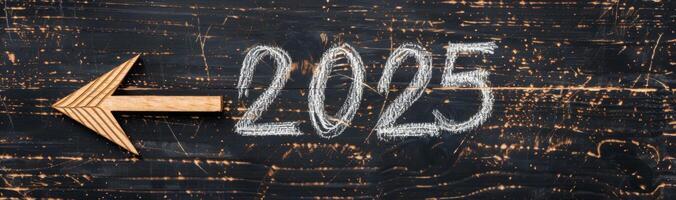 Wooden Arrow Pointing Left Towards 2025 on a Weathered Chalkboard Surface photo
