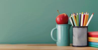 Red Apple on Stack of Notebooks With Colorful Pencils in Container Against a Green Background photo