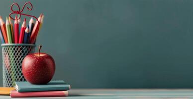 Red Apple on Stack of Notebooks With Colorful Pencils in Container Against a Green Background photo