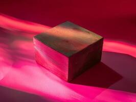 Wooden block on a pink surface with light. photo