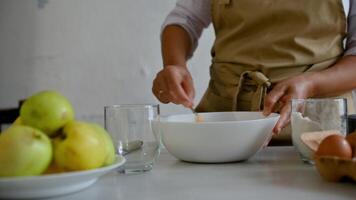 Baker mixing ingredients in a bowl with green apples, eggs, and flour on the table photo