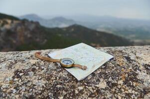 Compass and map on rough stone surface with scenic mountain view in the background photo