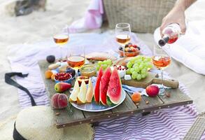 Man pouring wine having picnic on beach photo