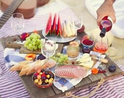 Man pouring wine having picnic on beach photo