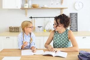 a woman and a little girl sitting at a table with a book photo