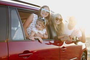 Happy smiling family with daughters in the car with sea background photo