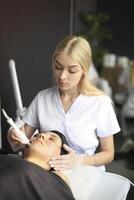Beautician using machine for radiofrequency lifting photo
