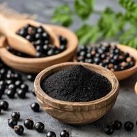 Black Currants and Powder Displayed in Rustic Bowls on Grey Countertop photo