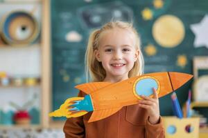 Smiling Girl Holding Rocket Toy in Classroom photo