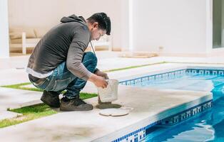 Worker removing trash from swimming pool filter basket. Man cleaning swimming pool garbage filter photo