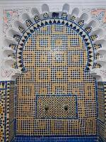 Exquisite fountain with complex traditional tiles and inscriptions. It includes the central basin, decorated with vibrant geometric patterns. About the fountain, it adds gypsum accents depth, texture photo
