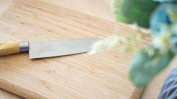 A Chefs Knife expertly placed on a Wooden Cutting Board surrounded by fresh Greenery video