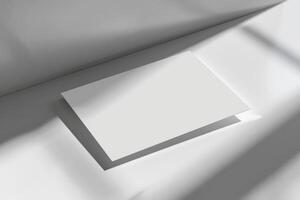 Top view of white business card with soft light and shadow on the wall for mockup photo