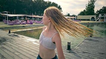 little blonde girl with wet hair dancing in Slow motion. The girl spins around herself. A carefree child is dancing outdoors on a lake and beach background video