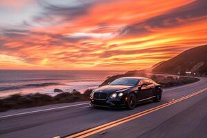 Prestige Luxury coupe cruising on coastal highway with the ocean stretching to the horizon and vibrant sunset sky photo