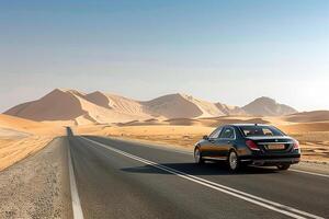 Sophistication Luxury sedan cruising on desert highway with expansive sand dunes and clear blue sky photo